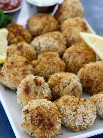 Baked mini crab cake bites served on a platter with lemon wedges and dipping sauces