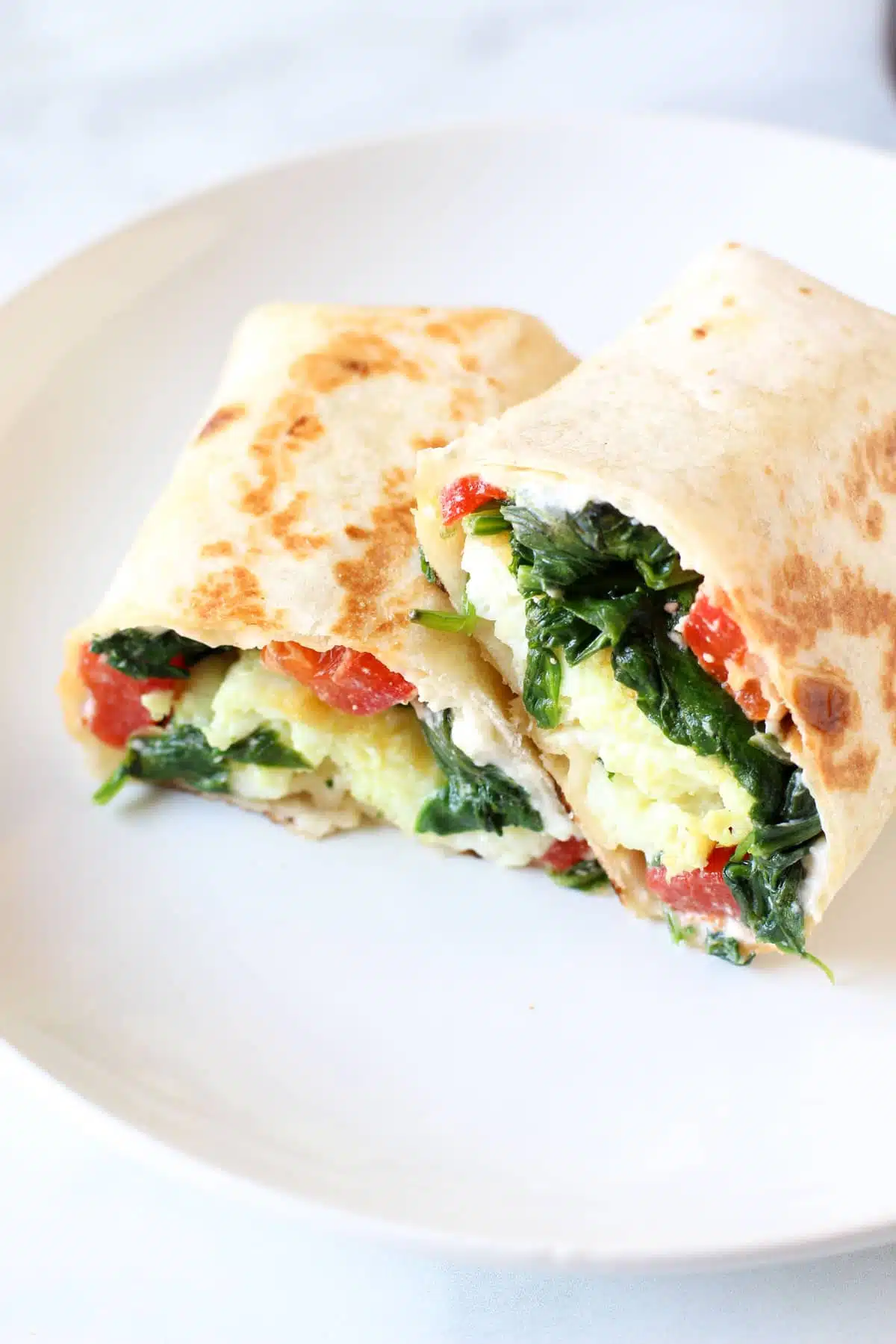 Egg white wrap with halal turkey spinach cheese and tomato folded and frozen for high protein breakfast meal prep