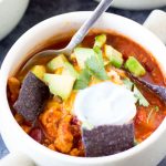 Turkey chili in a bowl with cream and chips.