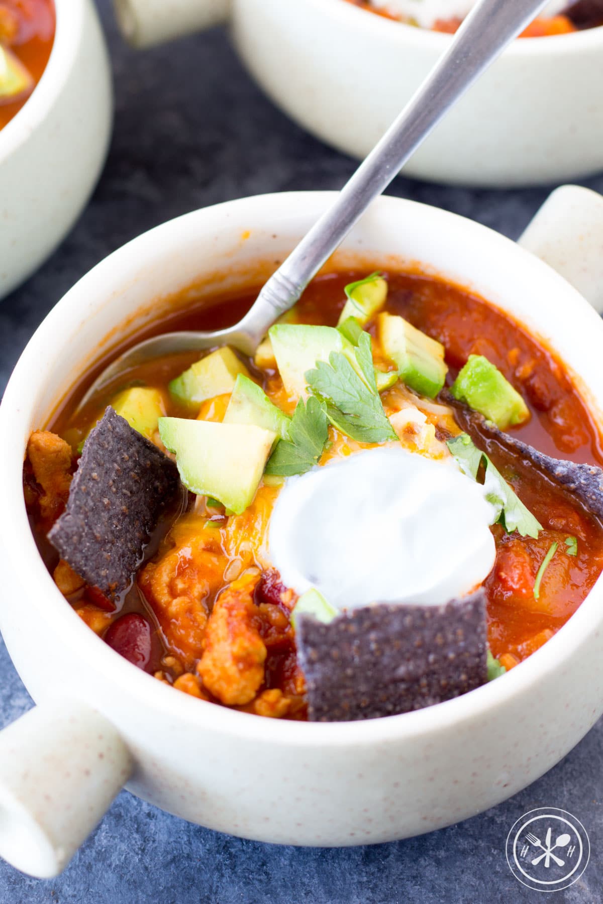 Turkey chili in a bowl with cream and chips.