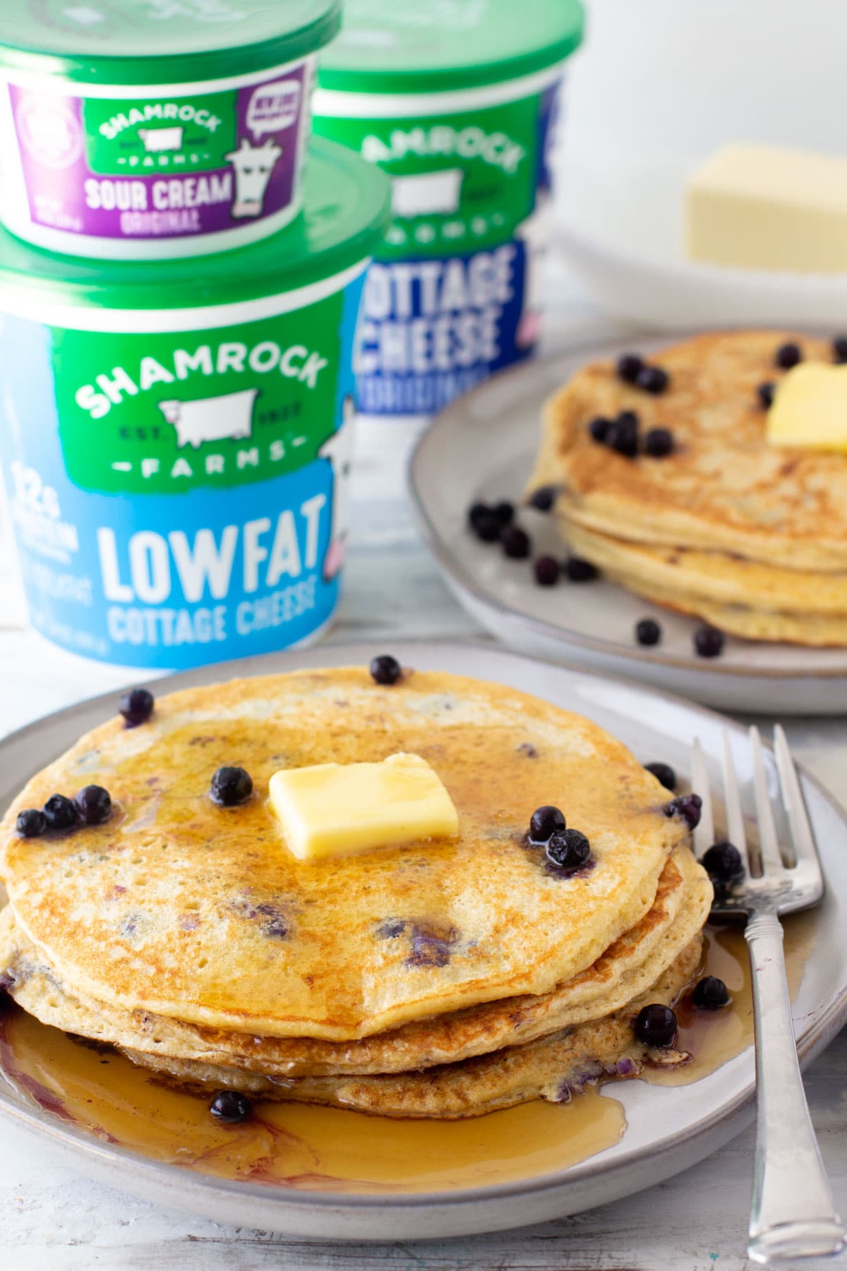 oatmeal cottage cheese pancakes with blueberry and shamrock cottage cheese containers metled butter on top