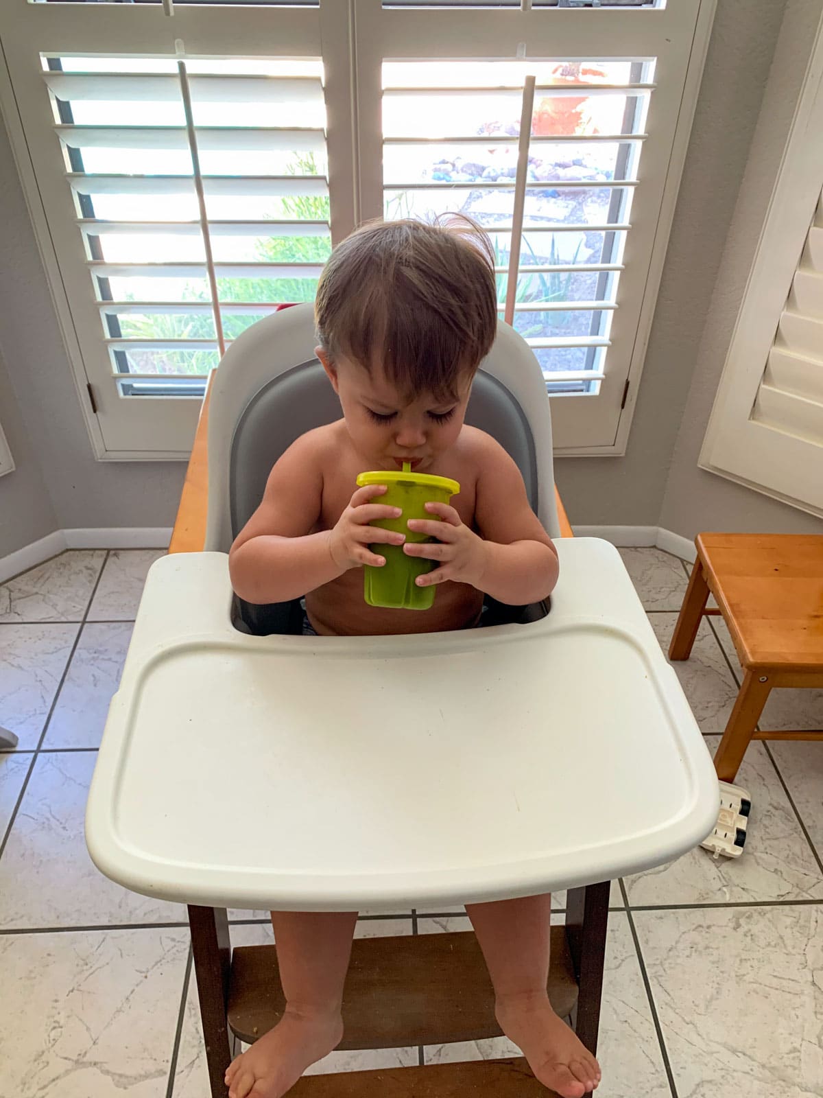toddler drinking a smoothie in his high chair