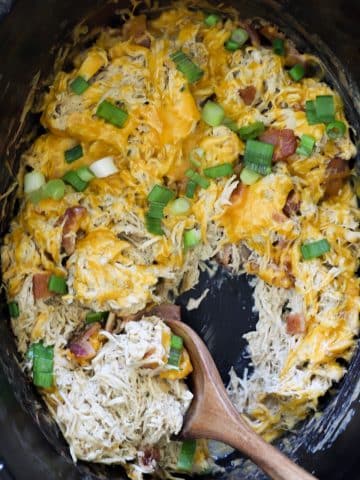 Spoonful of creamy crockpot crack chicken with bacon and melted cheddar in slow cooker
