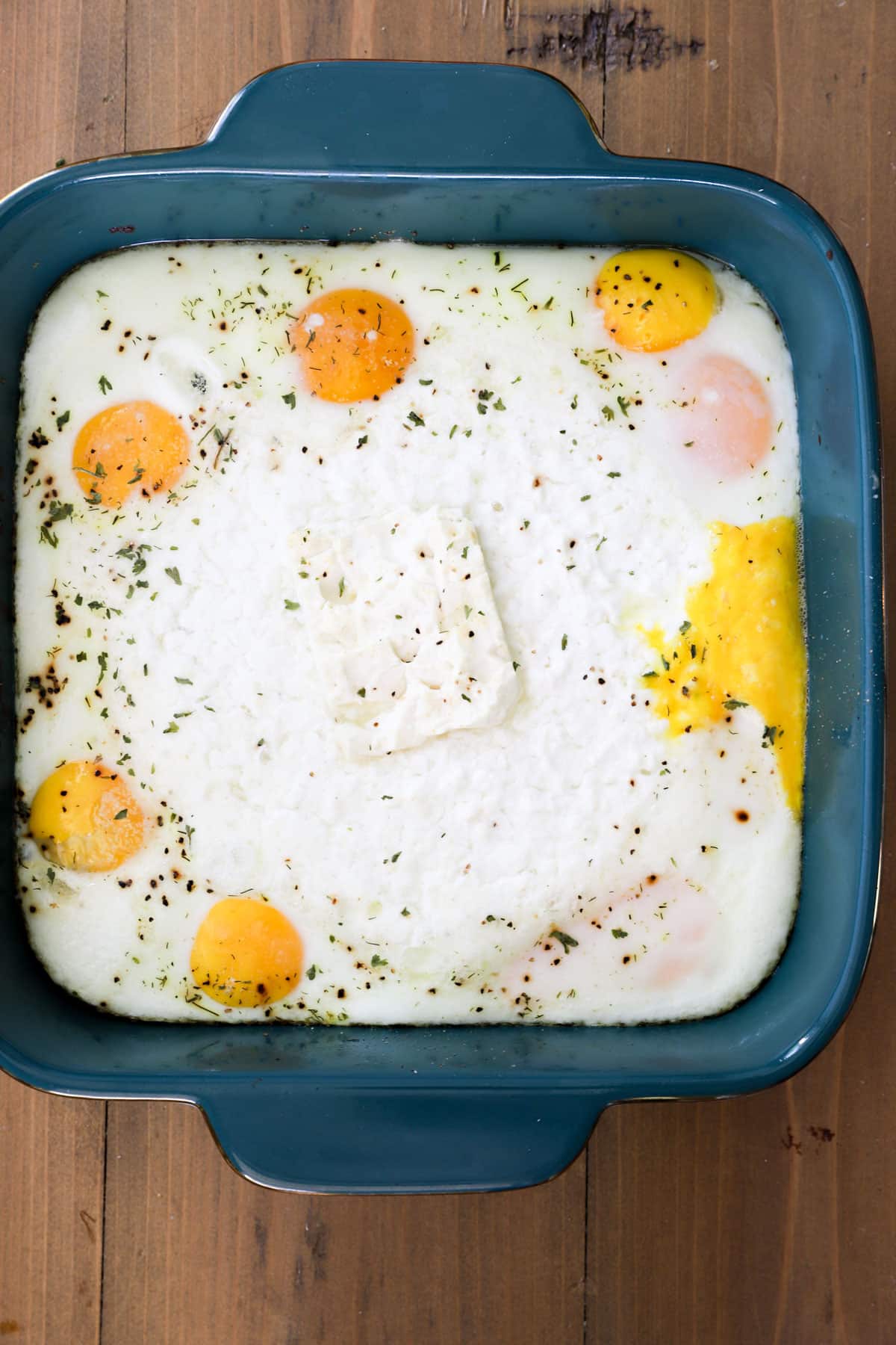 baked cottage cheese eggs with herbs in blue baking dish