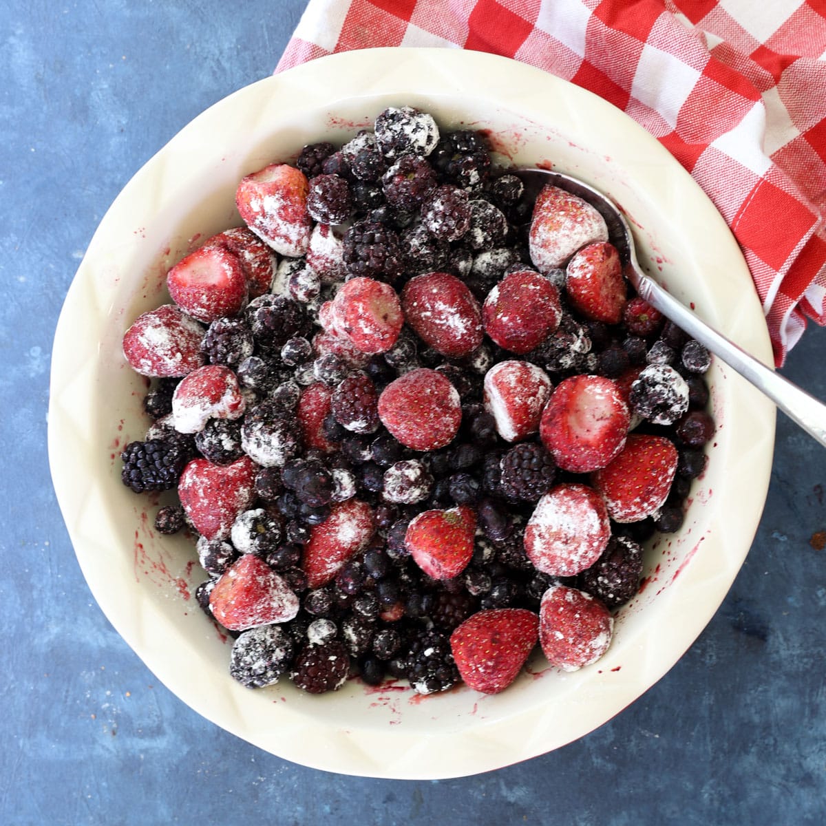Frozen mixed berries tossed with cornstarch in a white baking dish, ready for berry crumble